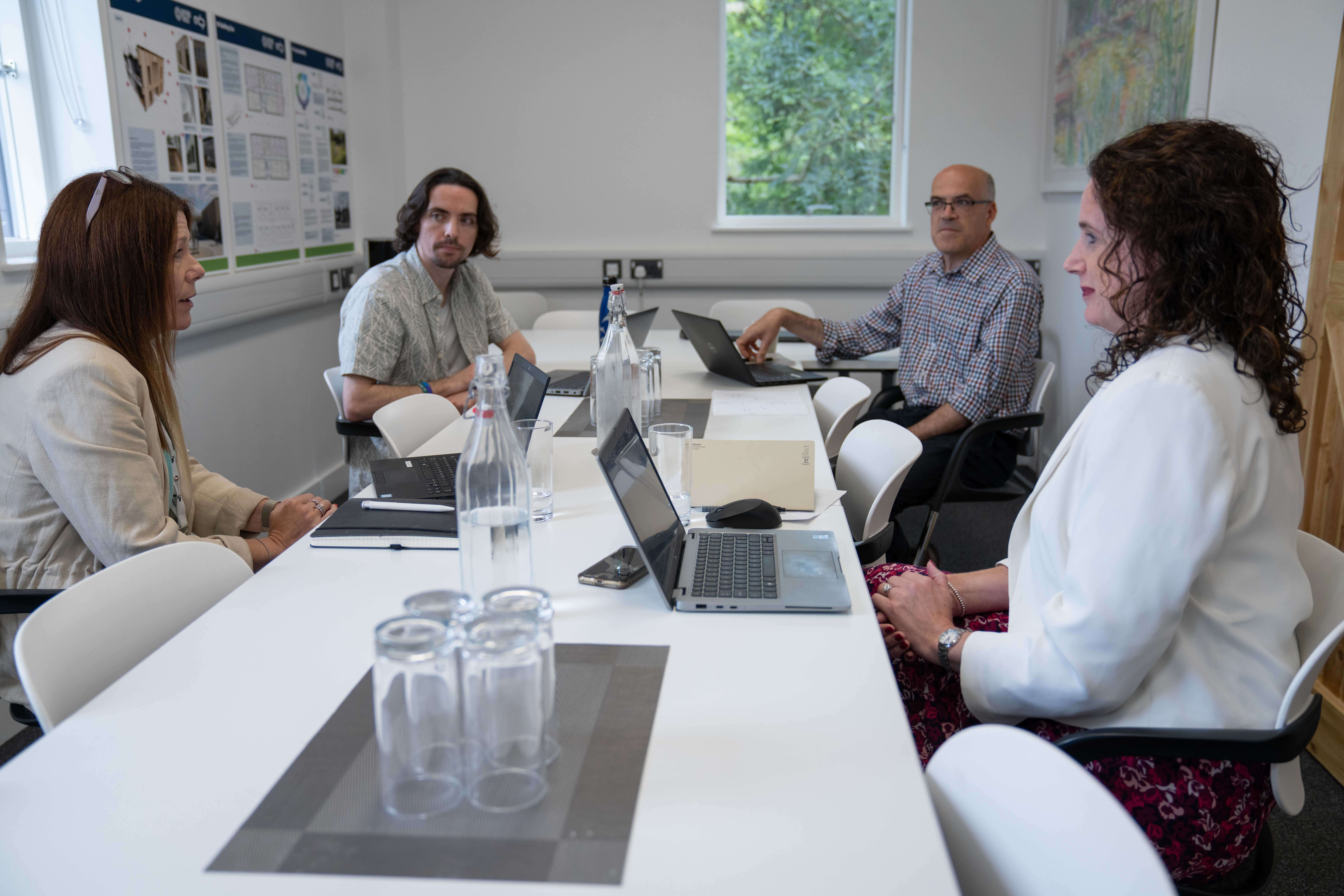 Team members sit around the large board room table in a meeting at the Wood Centre for Innovation.