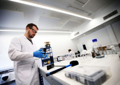 A person wearing a lab coat and glasses experiments in their technical workspace at the Wood Centre for Innovation.